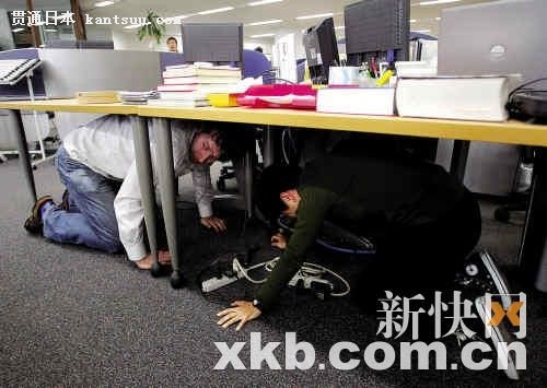 ■3月11日,在美联社日本东京分部,记者们躲在桌下避震。新华社发 ■3月11日,在美联社日本东京分部,记者们躲在桌下避震。新华社发