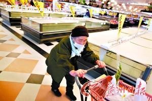 一位老人在超市购物,她的身后是已经空空荡荡的货架。 一位老人在超市购物,她的身后是已经空空荡荡的货架。