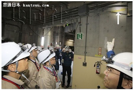 东京电力公司2月8日首次在东日本大地震后向媒体展示了福岛第二核电站。4号机组海水热交换器厂房内,一名东电员工(右)指出海啸到达的水位(箭头处)。(图片来源:共同社)