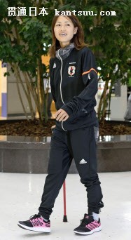 つえをつきながら笑顔で出発口に向かうサッカー女子日本代表の安藤梢選手(4日、成田空港)=共同